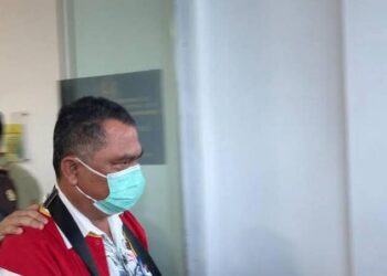 Kadishub Pematangsiantar, Julham Situmorang keluar dengan mengenakan rompi tahanan oranye, masker, dan tangan terborgol setelah menjalani pemeriksaan di Kejari Pematangsiantar.(simantab/putra purba)