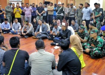 Bupati Simalungun (pegang mic) duduk di lantai, berdialog dengan pengunjuk rasa.(Simantab/ist)