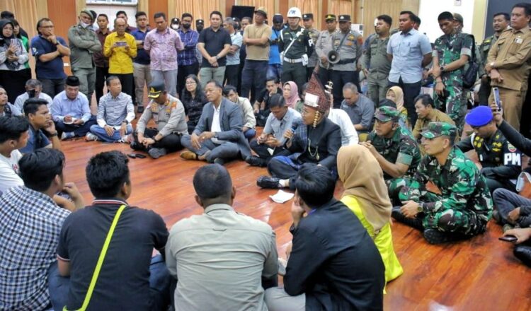 Bupati Simalungun (pegang mic) duduk di lantai, berdialog dengan pengunjuk rasa.(Simantab/ist)