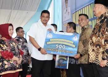 Penyerahan simbolis klaim Jaminan Kematian dan Jaminan Kecelakaan Kerja kepada penerima manfaat dari Gubsu Bobby Nasution kepada Wakil Bupati Simalungun Benny Sinaga.(Simantab/ist)
