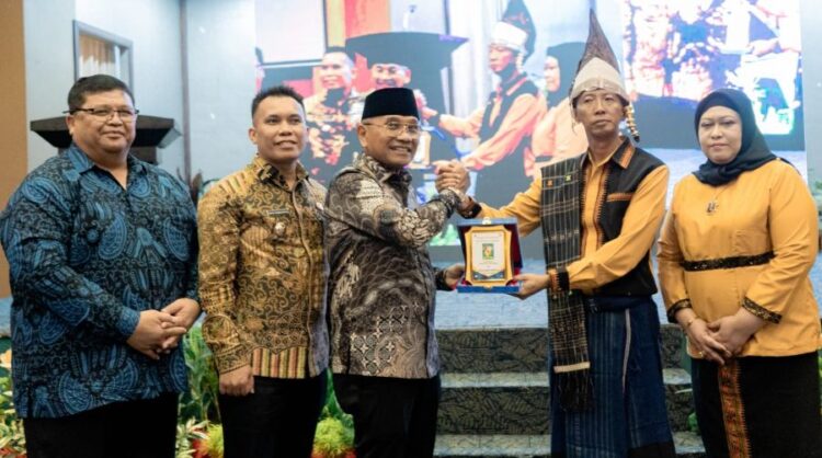 Bupati Simalungun Anton Achmad Saragih memberi plakat sebagai cindramata kepada Irfan Hergianto.(Simantab/ist)