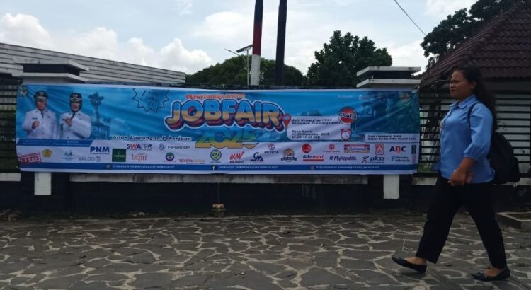 Seorang mahasiswi berjalan melewati spanduk Job Fair Pematangsiantar 2025 di di halaman Universitas HKBP Nommensen. (Simantab/Putra Purba)