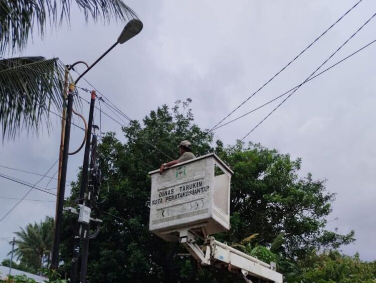 Petugas Dinas PKP Kota Pematangsiantar memperbaiki lampu jalan menggunakan armada sky lift yang kondisinya tampak usang.(Simantab/Putra Purba)