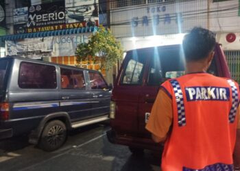Jukir di Jl Sutomo Pematangsiantar sedang mengatur kendaraan parkir.(Simantab/Putra Purba)