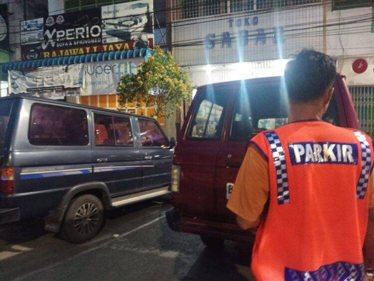 Jukir di Jl Sutomo Pematangsiantar sedang mengatur kendaraan parkir.(Simantab/Putra Purba)