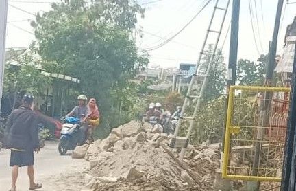 Tumpukan material dan sisa galian masih terlihat di sisi jalan, mempersulit pengguna jalan.(Simantab/Putra Purba)