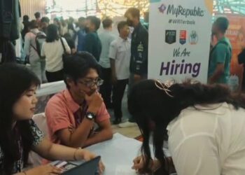 Seorang pelamar antusias mengisi persyaratan di salah satu booth perusahaan peserta Job Fair 2025 di Aula Universitas Nomensen.(Simantab/Putra Purba)