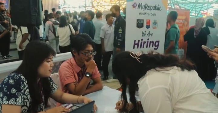 Seorang pelamar antusias mengisi persyaratan di salah satu booth perusahaan peserta Job Fair 2025 di Aula Universitas Nomensen.(Simantab/Putra Purba)